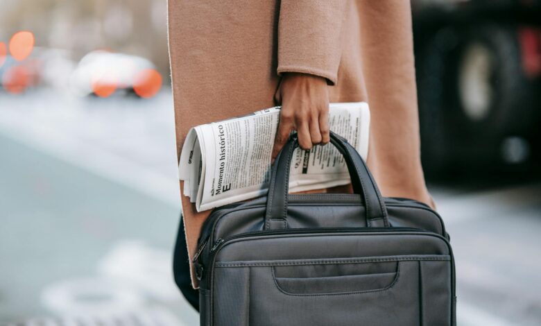 crop businesswoman with newspaper crossing road